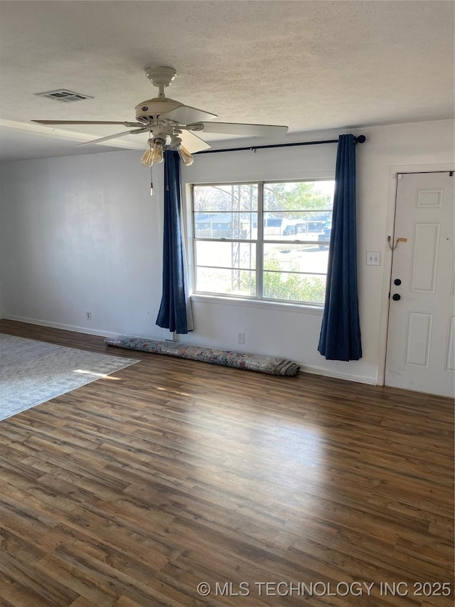 unfurnished room featuring ceiling fan, dark wood-type flooring, and a textured ceiling