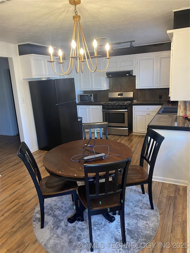 dining area featuring hardwood / wood-style floors, sink, a chandelier, and a textured ceiling