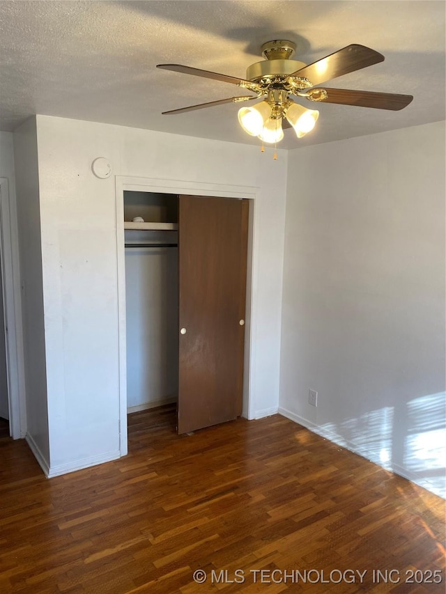 unfurnished bedroom featuring ceiling fan, dark wood-type flooring, a closet, and a textured ceiling