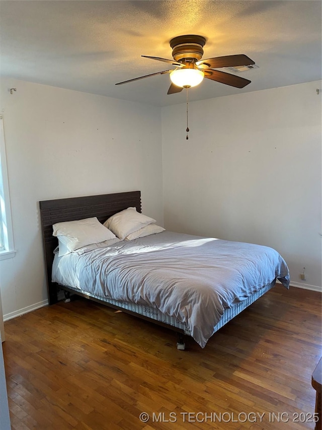 bedroom with ceiling fan, dark hardwood / wood-style flooring, and a textured ceiling