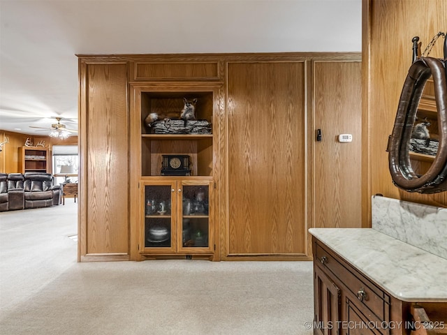 interior space with wood walls, ceiling fan, and carpet