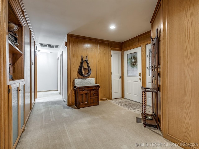 interior space with light colored carpet and wood walls