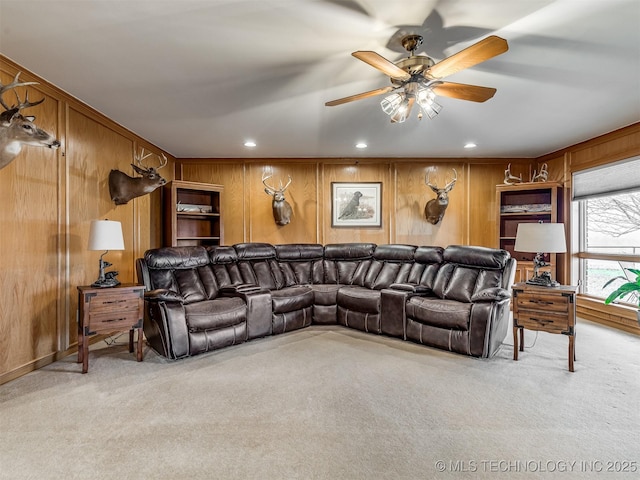 carpeted living room featuring ceiling fan and wood walls