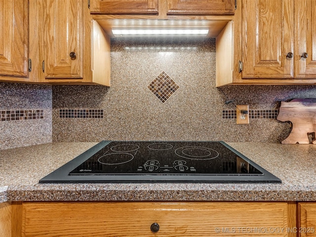 kitchen featuring tasteful backsplash, brown cabinetry, and black electric cooktop