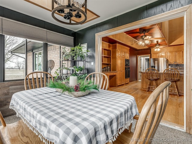 dining space with ornamental molding, ceiling fan, and light wood-style flooring