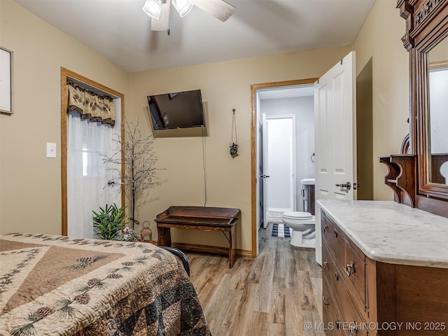 bedroom featuring baseboards, light wood-type flooring, and ensuite bath