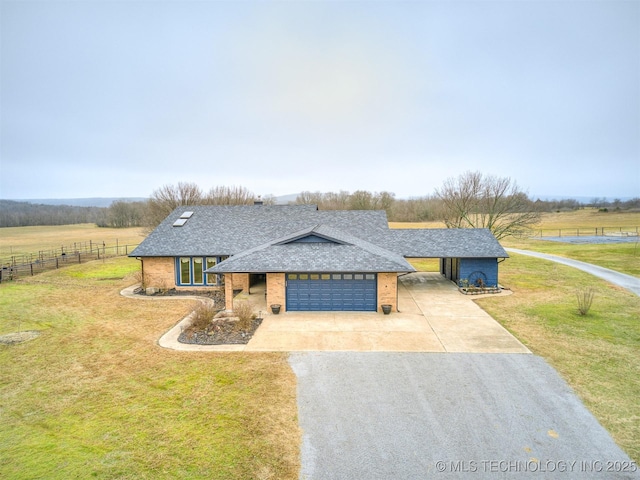 view of front facade with a garage, a front yard, and a rural view