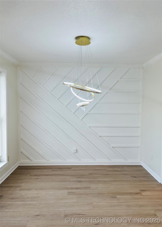 spare room with wood-type flooring, ornamental molding, and an inviting chandelier