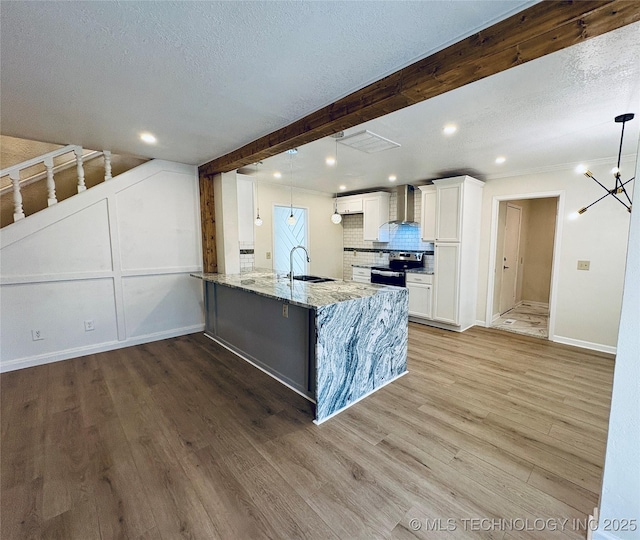 kitchen featuring sink, white cabinets, kitchen peninsula, beam ceiling, and wall chimney exhaust hood