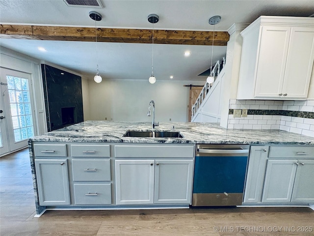 kitchen featuring pendant lighting, sink, stainless steel dishwasher, and white cabinets