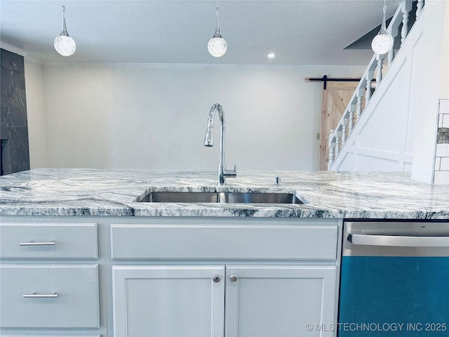 kitchen with sink, light stone counters, decorative light fixtures, stainless steel dishwasher, and a barn door