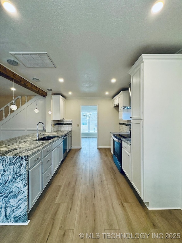 kitchen featuring sink, white cabinetry, stainless steel appliances, light stone counters, and decorative light fixtures