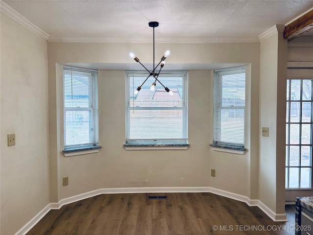 unfurnished dining area featuring an inviting chandelier, ornamental molding, dark hardwood / wood-style flooring, and a textured ceiling