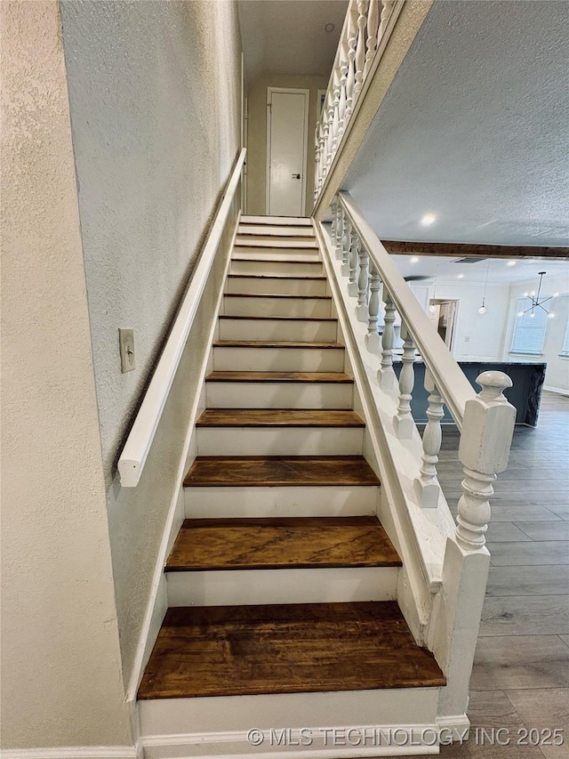 staircase featuring wood-type flooring and a textured ceiling