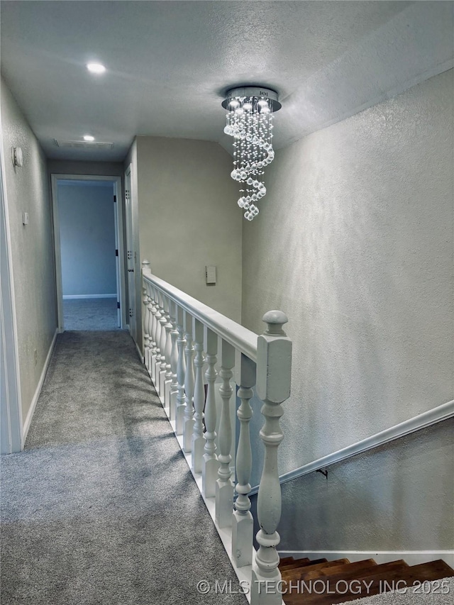 staircase featuring carpet, a textured ceiling, and a chandelier