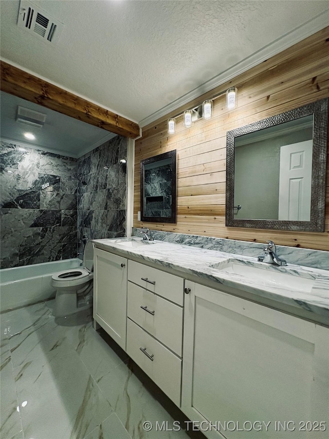 full bathroom with tiled shower / bath, wooden walls, vanity, toilet, and a textured ceiling