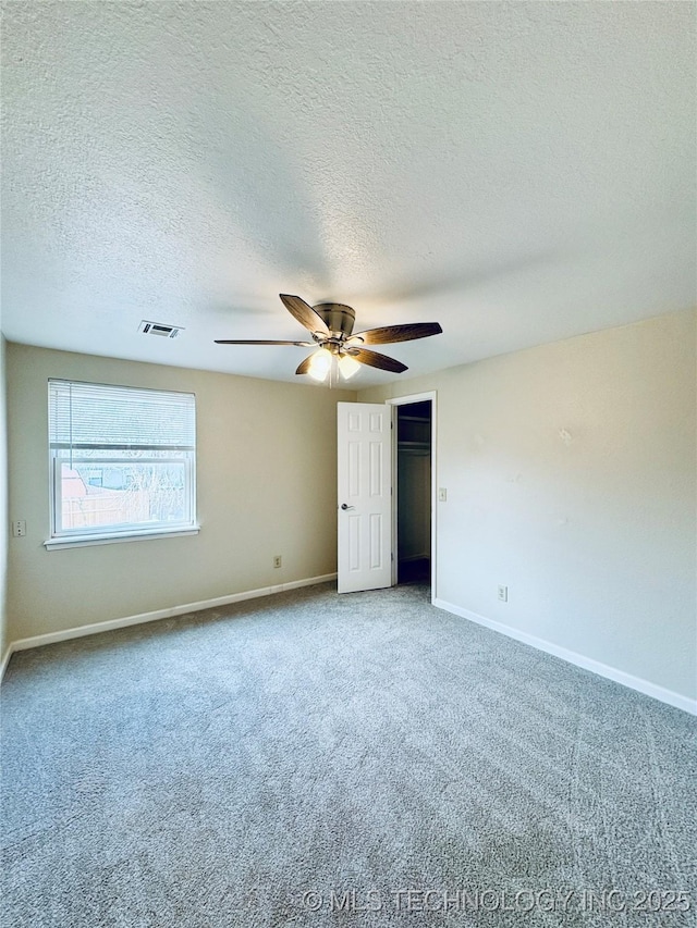 unfurnished bedroom featuring ceiling fan, carpet flooring, a closet, and a textured ceiling