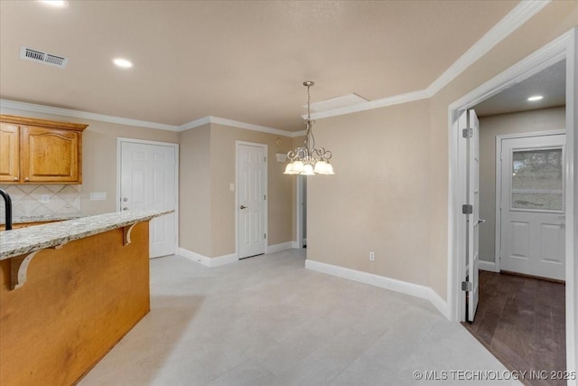 kitchen with crown molding, a kitchen breakfast bar, a notable chandelier, pendant lighting, and backsplash