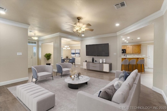 living room featuring ornamental molding and ceiling fan with notable chandelier