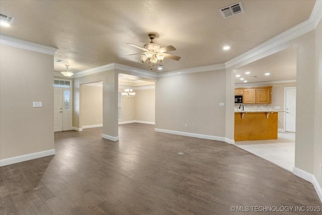 unfurnished living room with ornamental molding, wood-type flooring, and ceiling fan with notable chandelier