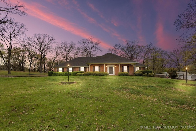 view of front facade featuring brick siding and a yard