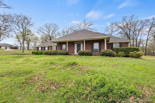 view of front of property with a front yard, brick siding, and roof with shingles