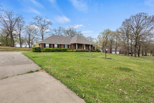 single story home with brick siding, a front yard, and concrete driveway