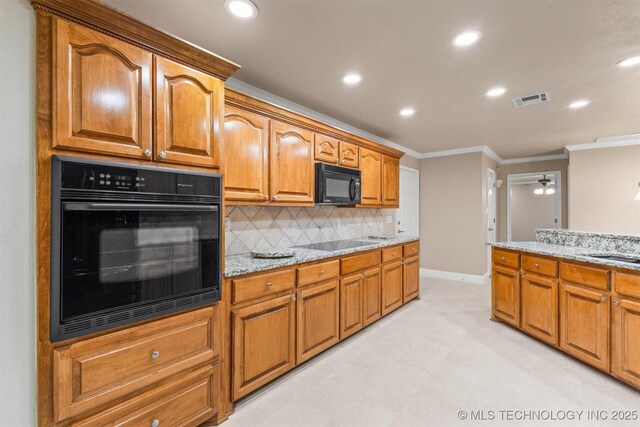 kitchen with visible vents, black appliances, ornamental molding, and light stone counters