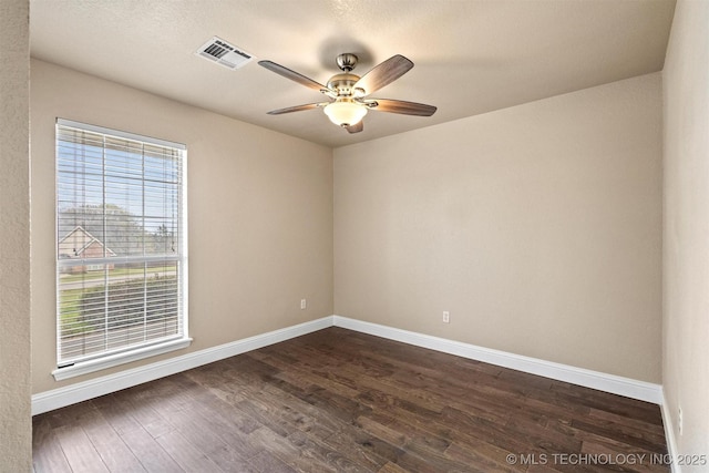 unfurnished room featuring a ceiling fan, dark wood finished floors, baseboards, and visible vents
