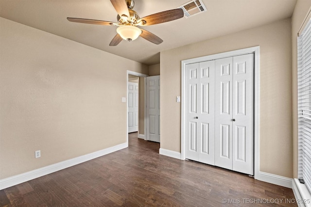 unfurnished bedroom with baseboards, visible vents, a closet, and dark wood-style flooring