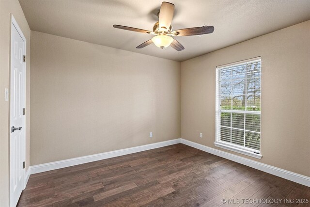 spare room with baseboards, dark wood-style floors, and ceiling fan