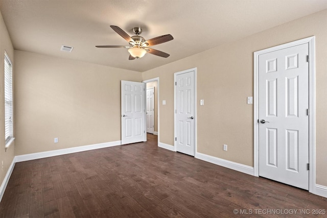 unfurnished bedroom featuring baseboards, dark wood-style flooring, visible vents, and a ceiling fan