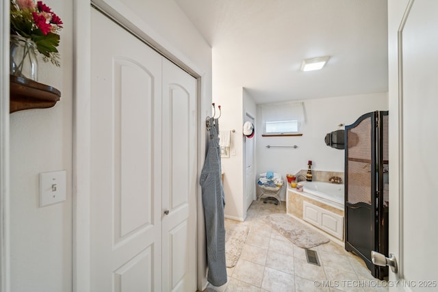 bathroom with a relaxing tiled tub and tile patterned floors