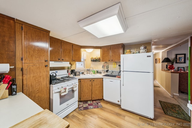 kitchen with light wood-type flooring, sink, and white appliances