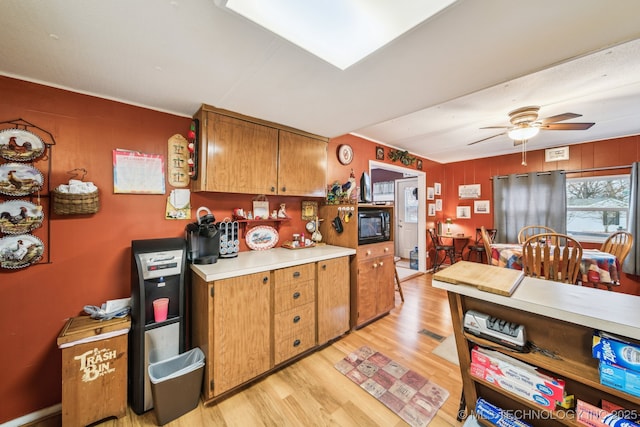 kitchen with light hardwood / wood-style flooring, black microwave, and ceiling fan