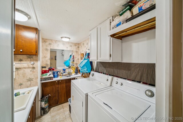 clothes washing area featuring sink, light tile patterned floors, cabinets, washer and dryer, and a textured ceiling