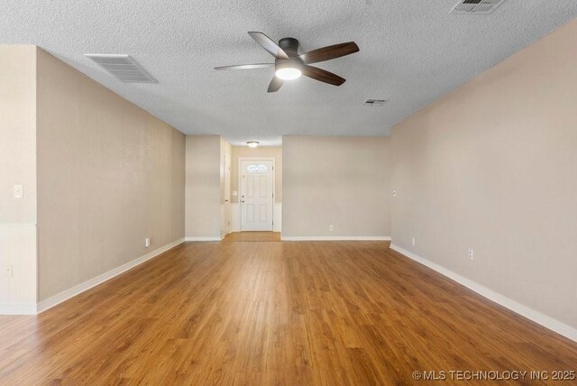 unfurnished room with ceiling fan, wood-type flooring, and a textured ceiling