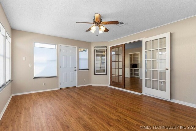 empty room with french doors, ceiling fan, wood-type flooring, and a textured ceiling