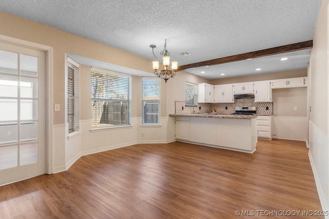 kitchen with white cabinetry, hanging light fixtures, light hardwood / wood-style floors, kitchen peninsula, and light stone countertops