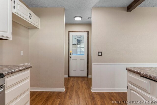 kitchen featuring white cabinetry, wood-type flooring, and a textured ceiling