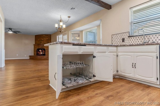 kitchen featuring light hardwood / wood-style flooring, white cabinets, a textured ceiling, and a fireplace