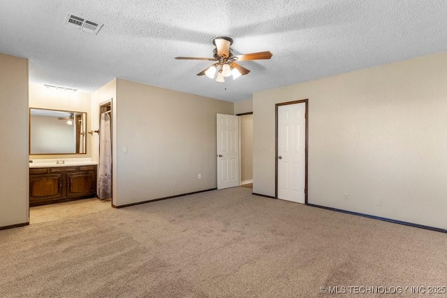 unfurnished bedroom with connected bathroom, sink, light colored carpet, ceiling fan, and a textured ceiling