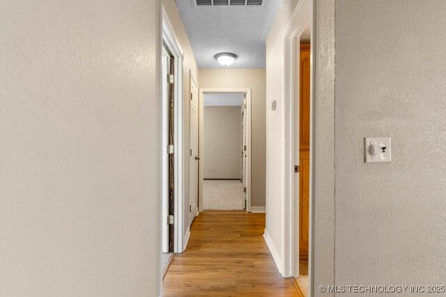 hallway featuring a textured ceiling and light hardwood / wood-style flooring