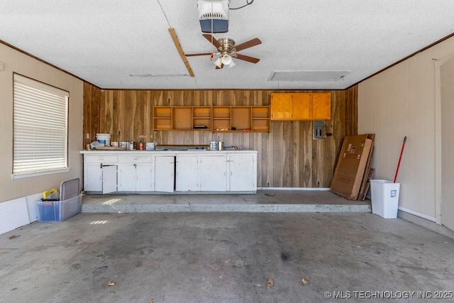 garage with a garage door opener, ceiling fan, and wood walls