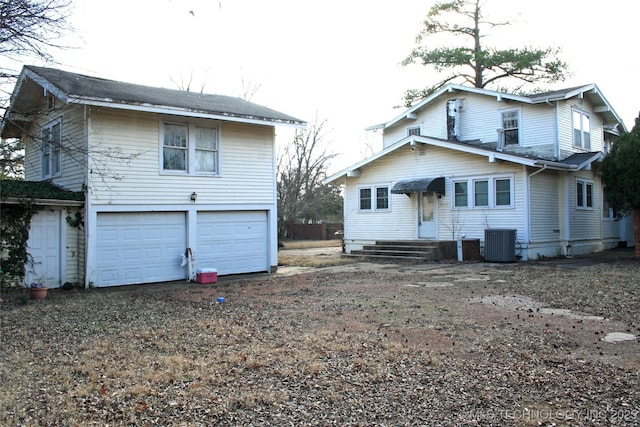 rear view of property featuring a garage and central air condition unit