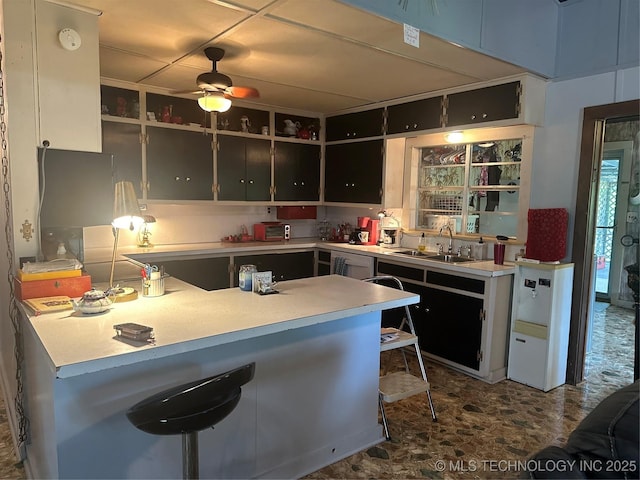 kitchen with sink, kitchen peninsula, ceiling fan, and a breakfast bar