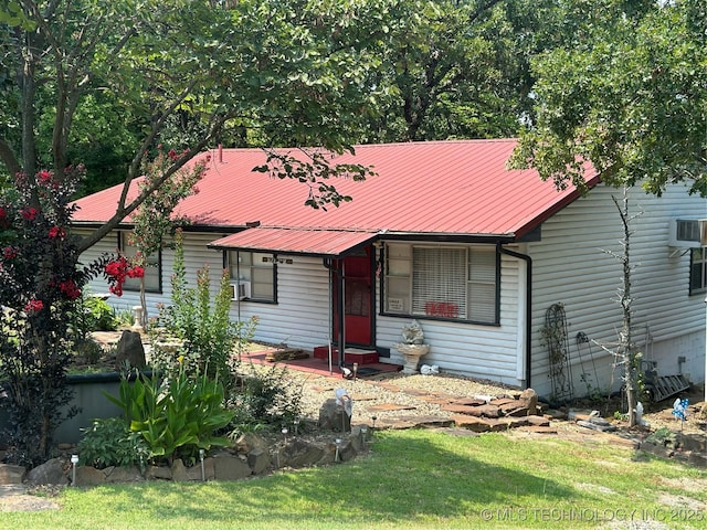 view of front facade featuring a wall unit AC and a front lawn