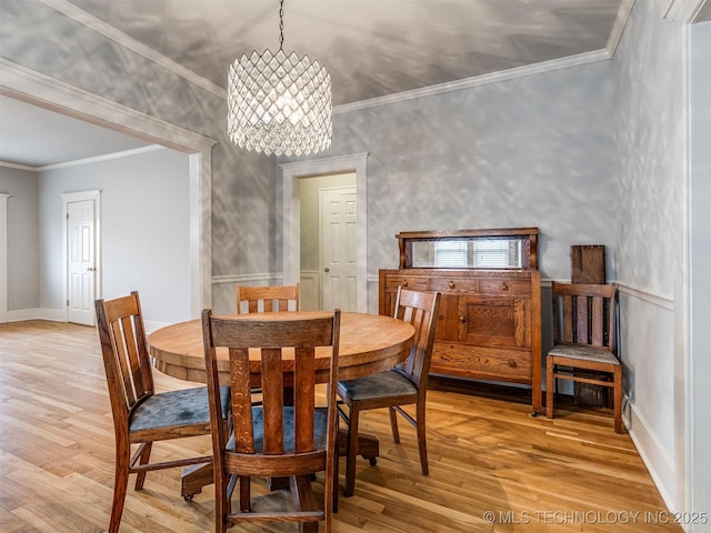 dining area featuring crown molding, an inviting chandelier, and light hardwood / wood-style flooring