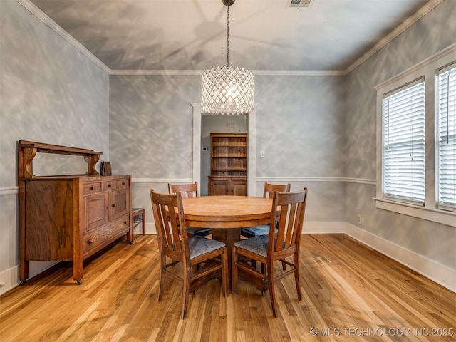 dining area featuring crown molding, a notable chandelier, and light wood-type flooring