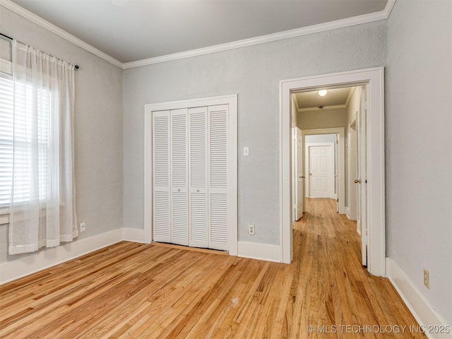 unfurnished bedroom with crown molding, a closet, and light wood-type flooring